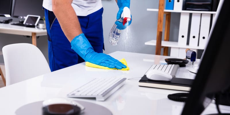 Janitor cleaning white desk in modern office